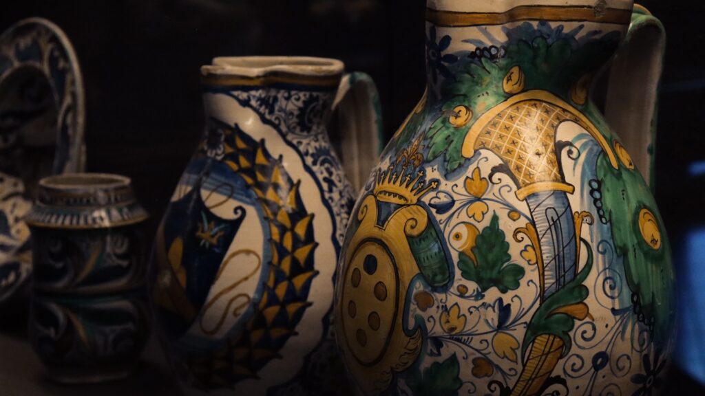 Colorful majolica ceramic jugs with blue, green, and yellow patterns displayed in International Museum of Ceramics in Faenza