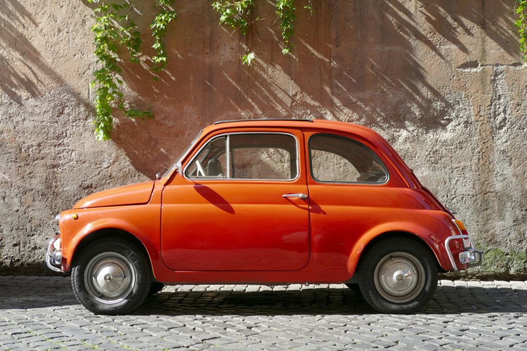 Orange vintage car on a cobblestone street for deciding whether to rent a car in Emilia-Romagna